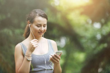 Sevimli genç kadın yeşil bir parkta yolda koşu sırasında müzik.