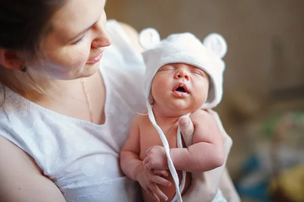 かわいい 若い母親は彼女の腕で子供のニット帽子で彼女の睡眠の生まれたばかりの息子を保持しています 幸せな子供時代 母乳育児のコンセプト — ストック写真