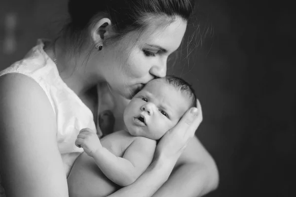 年轻可爱的母亲抱在怀里亲吻熟睡的新生儿子 一个快乐的童年 母乳喂养的概念 白色和黑色 — 图库照片
