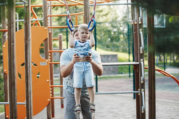 若い父親と青い シャツの金髪の少年は 夏に子供の遊び場で階段を登る — ストック写真