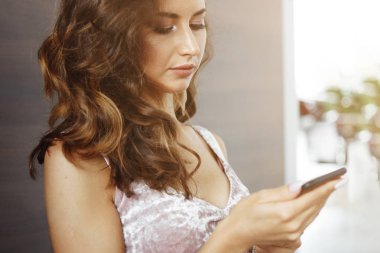 Sevimli genç kadın uzun saçlı bir smartphone içinde görünüyor, bir posta sosyal medyada geçici.