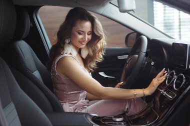 Uzun kıvırcık saçlı güzel güzel kız siyah bir arabada oturuyor. Sadece bir araba bayilik olarak al. Bir araç satın alma kavramı.