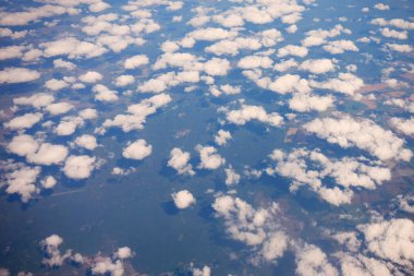 Manzara, bir uçak penceresinden bulutların arasından Dünya yüzeyinin.