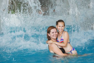 Güzel bir kadın ve kızı gülmek ve aqua park'mavi suda ayakta orada hug.