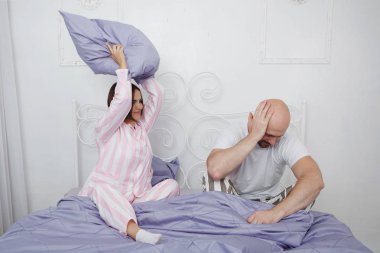 Genç güzellik ve kel sakallı adam pijama yastık mavi keten ile yatakta yendi.