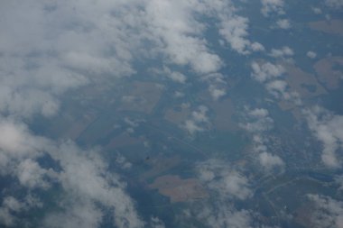 Manzara, bir uçak penceresinden bulutların arasından Dünya yüzeyinin.