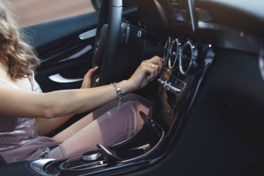 Uzun kıvırcık saçlı güzel güzel kız siyah bir arabada oturuyor. Sadece bir araba bayilik olarak al. Bir araç satın alma kavramı.