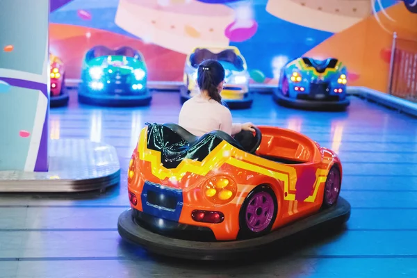 Young pretty girl in glasses with a pigtail riding a toy electric car. Joyfull weekend. Pleasure to travel. — Stock Photo, Image