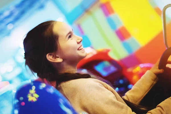 La ragazza carina giovane con un codino sorride gioca nella macchina mangiasoldi. Fine settimana pieno di gioia. Divertimento nel gioco . — Foto Stock