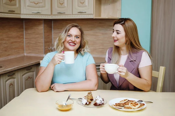 Dos novias mujeres en la cocina se están divirtiendo y comiendo comida . — Foto de Stock