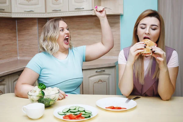 台所で女性の 2 つのガール フレンドの楽しい時を過してそして食糧を食べる. — ストック写真