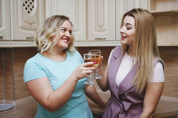 Dos amigas mujeres en la cocina se divierten y beben vino . — Foto de Stock