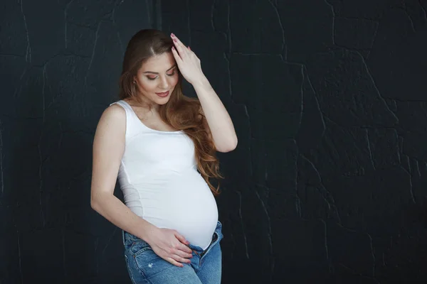 Mooie Zwangere Vrouw Met Lange Haren Een Wit Shirt Spijkerbroek — Stockfoto