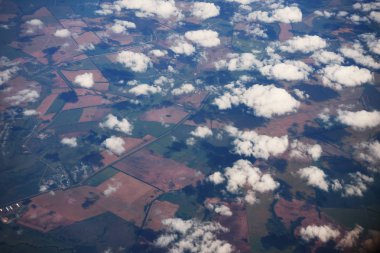 Manzara, bir uçak penceresinden bulutların arasından Dünya yüzeyinin.