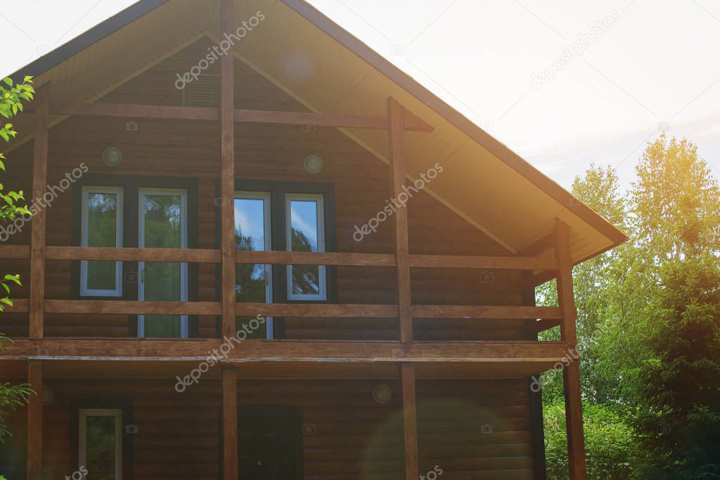 Wooden house of round logs with a balcony and windows.