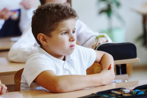 一个年轻的小学生坐在学校课堂的桌子旁 — 图库照片