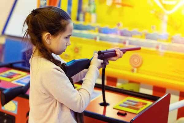 Young pretty girl in glasses with pigtails shoots a toy machine out of a toy gun. Joyfull weekend. Pleasure and luck in the game.