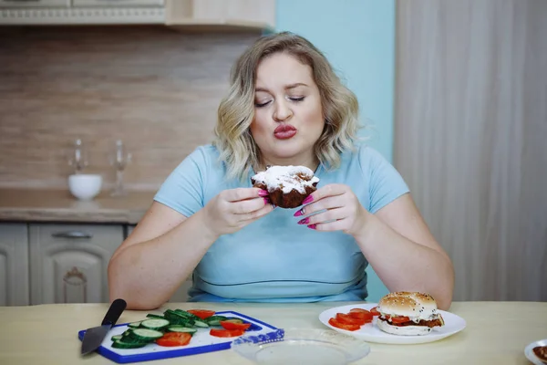 年轻漂亮的胖金发女人准备吃一个纸杯蛋糕 健康饮食 抗肥胖的理念 — 图库照片