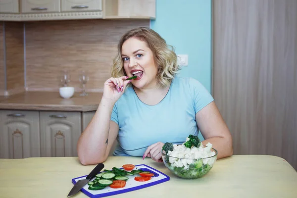 年轻漂亮的胖金发碧眼的女人吃绿色黄瓜和花椰菜 健康饮食 抗肥胖的理念 — 图库照片