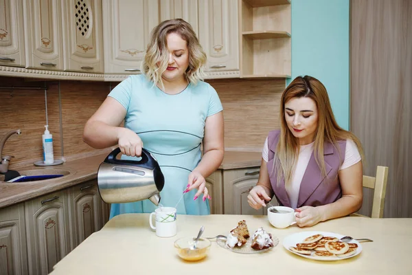 年轻漂亮的胖金发女郎把茶壶里的水倒进杯子里给她的朋友喝 健康饮食 与超重作斗争的理念 — 图库照片