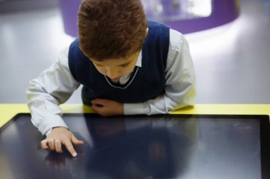 Okul çocuğu dikkatle sarı bir interaktif beyaz tahta ile çalışma.