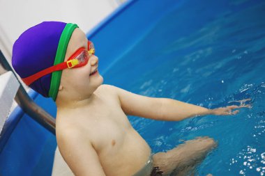 Bir Mavili oğlanın kap ve gözlük havuzu merdivenlerde oturuyor. Sağlıklı bir yaşam tarzı. Aquatherapy. Yüzme rehabilitasyon. Dalış.