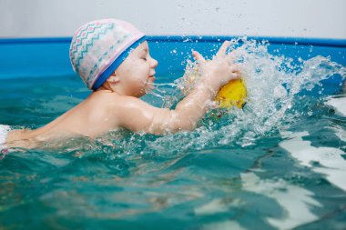 Bebek havuzda yüzmeyi öğrenir. Sağlıklı yaşam, su rehabilitasyon, aquatherapy.