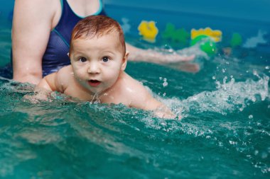 Anne ile bebek egzersizleri havuzun içinde. Sağlıklı yaşam, su rehabilitasyon, aquatherapy.