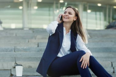 Genç smartphone ile gülümseyen kadın güzel ve kahve fincanı şehir sokak parlayan ışıklar arka plan üzerinde kağıt. Evet. Vintage sesi filtre efekti renk stili.