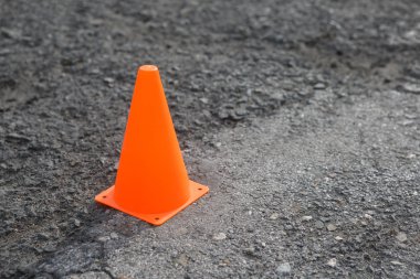 Plastik turuncu yol koni gri asfalt üzerinde.