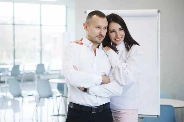 Teamwork of office staff. A businessman coach in a white shirt and a woman standing near a flipchart are happy about a good deal. Business training. Personal growth. Gender equality.