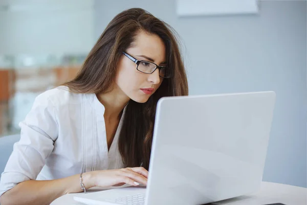 Geschäftsfrau Mit Brille Und Weißer Bluse Sitzt Einem Tisch Mit lizenzfreie Stockfotos