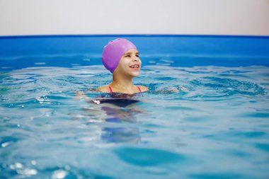 Lila şapkalı kız eğleniyor, havuzda yüzme. Dalış. Sağlıklı yaşam, su rehabilitasyon, aquatherapy.