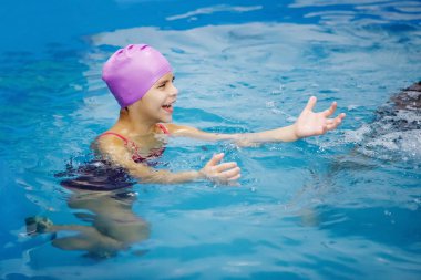 Lila şapkalı kız eğleniyor, havuzda yüzme. Dalış. Sağlıklı yaşam, su rehabilitasyon, aquatherapy.