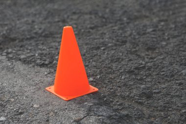 Plastik turuncu yol koni gri asfalt üzerinde.
