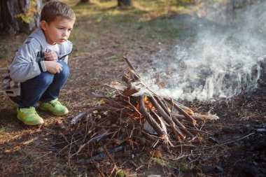 Çocuk sonbahar ormanda bir yangın yap.