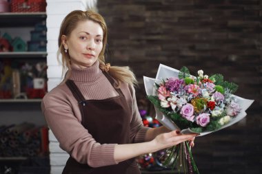 Önlük kadında çok orta yaşlı çiçekçi bir buket çiçek salon için bir düğün ya da yıldönümü şenlikli bir hediye yapar.