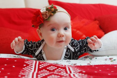 Hoş beş aylık bebek baş elbisesini kırmızı bir arka plan üzerinde bir çiçek kız bebek. Anne bakım. Çocuk Bakımı. Yakın çekim.