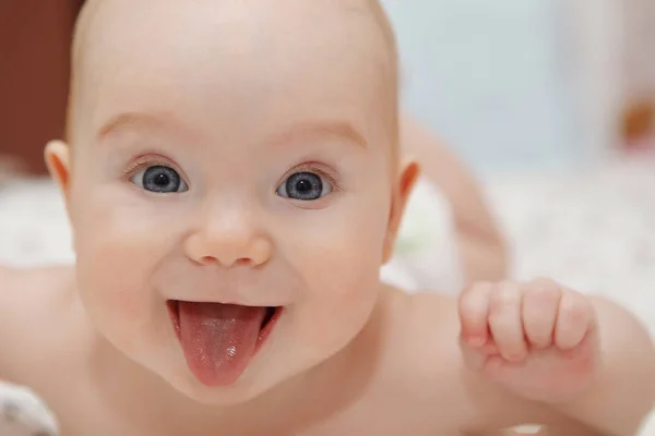 美丽的五个月蓝眼睛女婴躺在她的肚子上 表现出舌头 各种情绪和脸上的微笑 婴儿的样子 产妇护理 — 图库照片