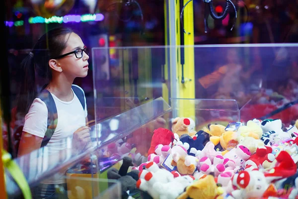 可爱的女孩在白色 T恤背包和眼镜在游戏机玩街机 — 图库照片