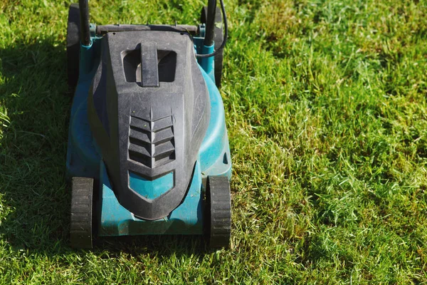 Cutting green grass electric lawn mower, selective focus