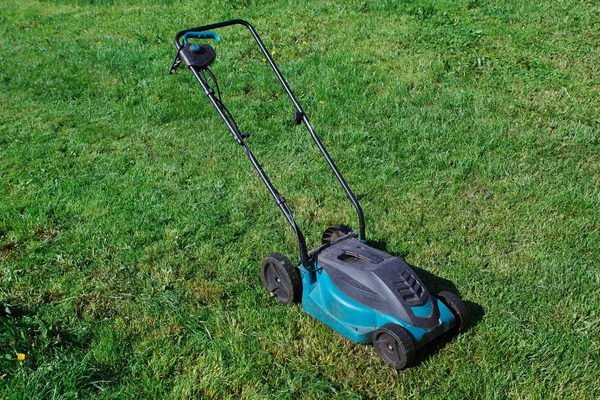 Cutting green grass electric lawn mower, selective focus