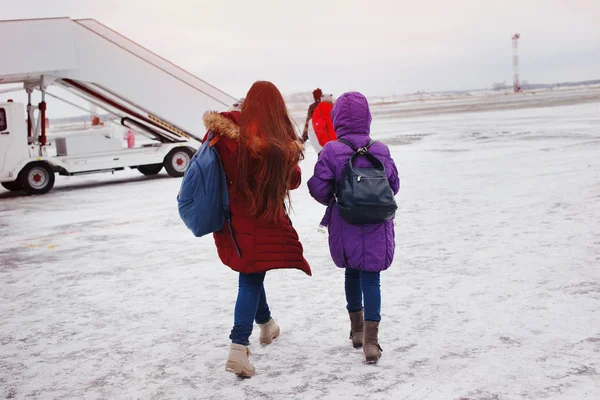 Δύο Κορίτσια Ευτυχισμένη Τουρίστες Σακίδια Μεταβείτε Αεροπλάνο Ένα Χιονισμένο Πεδίο — Φωτογραφία Αρχείου