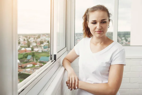 Όμορφη Γυναίκα Στο Λευκό Shirt Στέκεται Από Παράθυρο Στο Μπαλκόνι — Φωτογραφία Αρχείου