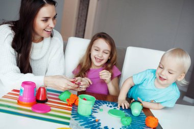 Anne ile oğlu ve kızı evde masada oturan hamuru ile oynamak