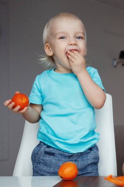 Yakışıklı sarışın ve mavi gözlü portakal yeme