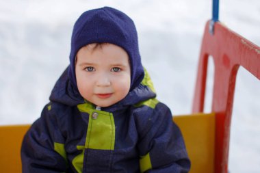Mavi kapüşonlu bir çocuk oyun alanı, kış erkek bebek giymiş