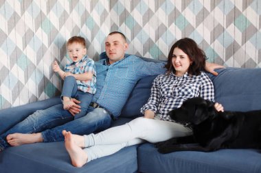 Genç aile ile Siyah labrador retriever köpek mavi kanepede oturan