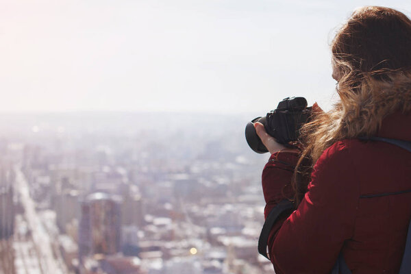 Woman looking down from roof and taking pictures on camera