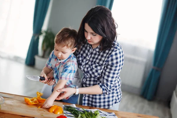 mom and son cooking vegetables at table in kitchen